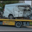A tow truck transports a damaged vehicle.