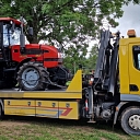 Tow truck, who lifts a large tractor from a rural area.