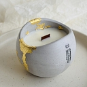 Natural wax candle in a plaster container with gold decor