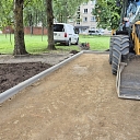 an excavator levels the ground around new sidewalk elements