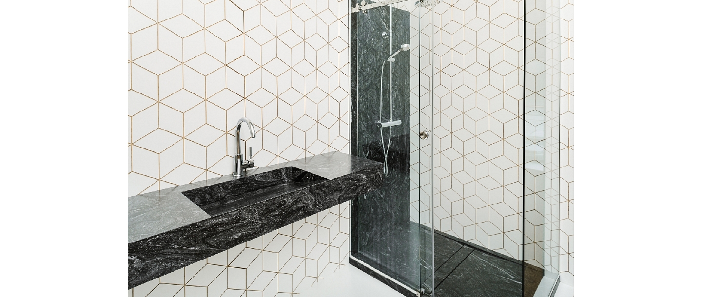 Поверхность ванной комнаты с раковиной и душевой кабиной остается облицованной панелью из материала Corian®