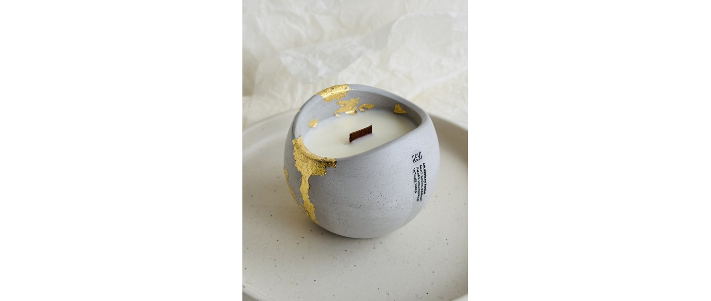 Natural wax candle in a plaster container with gold decor