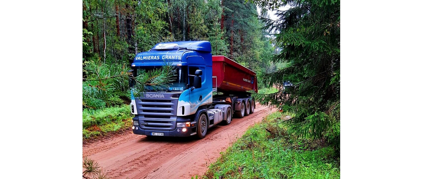 Scania kravas automašīna pārvadā grants pa meža ceļu